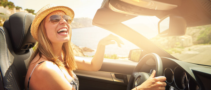 happy woman driving a convertible protected by an extended warranty in the sunshine