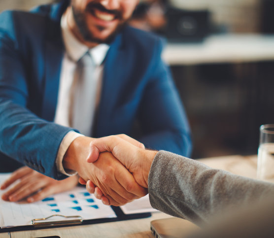 two business people shaking hands over a desk