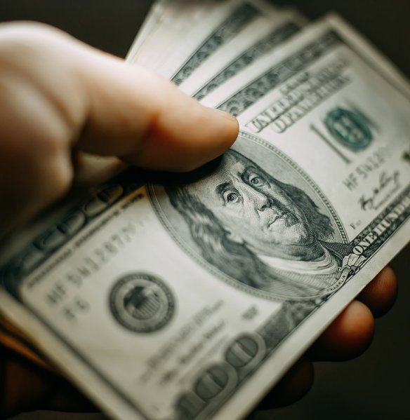 hand with stack of hundred dollar bills